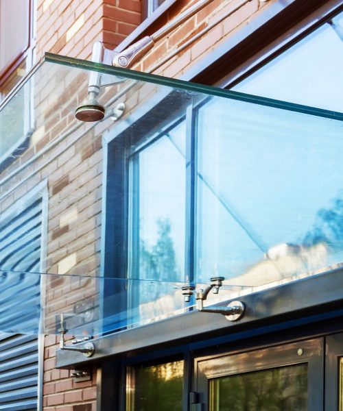 Transparent,Glass,Awning,Over,Front,Door,Of,Multistory,Brick,Apartment