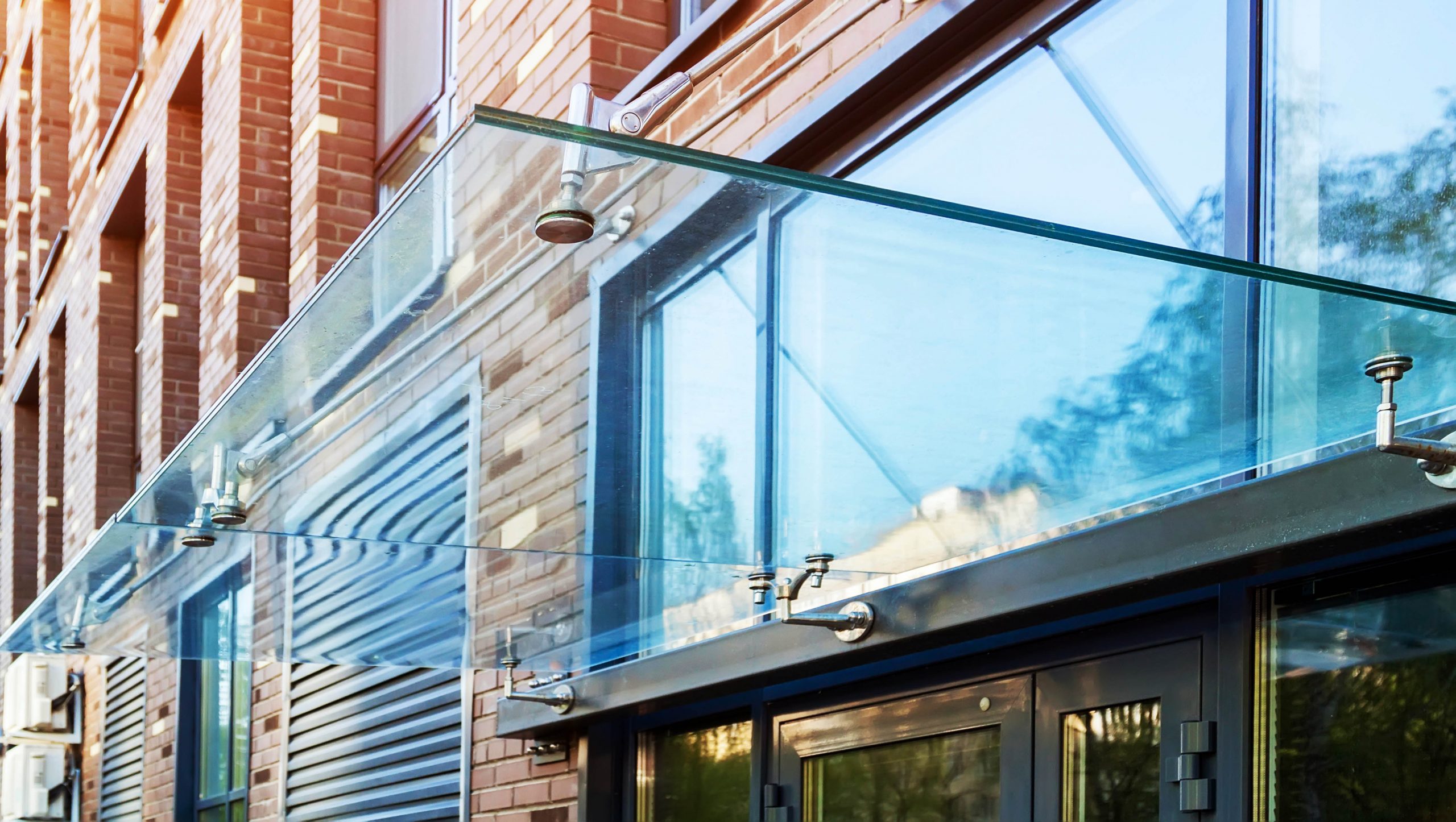 Transparent,Glass,Awning,Over,Front,Door,Of,Multistory,Brick,Apartment
